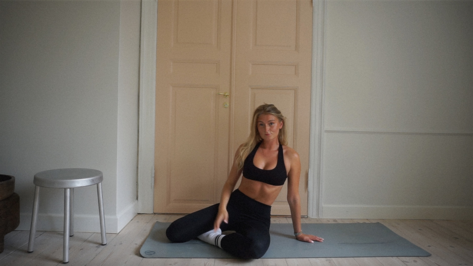 Frederikke Adamsen seated on a yoga mat in a neutral-toned room